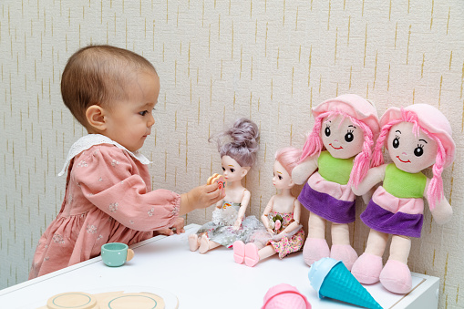 Closeup of toddler playing with baby doll at home
