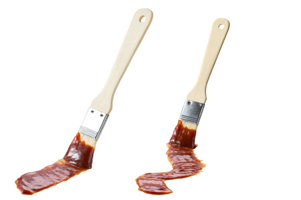 Barbecue brush dipped in hot barbecue sauce isolated on a white background. bbq sauce and brush. stock photo