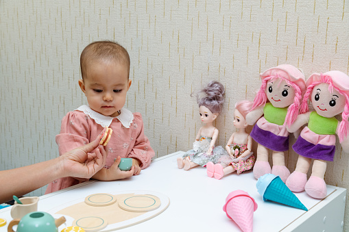 Closeup of toddler playing with baby doll at home