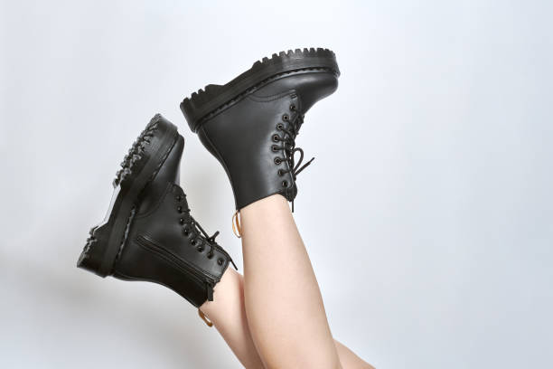 istock Woman legs in black combat boots on high heel platform with lug soles upside down, white background 1456316729