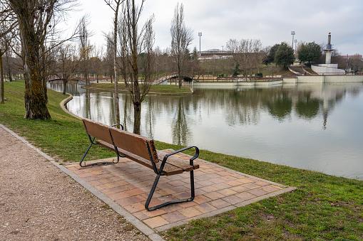 Wooden bench to sit and rest in a public park overlooking the crystal clear lake