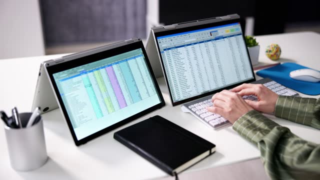 Businesswoman's Hand Examining Spreadsheet On Laptop