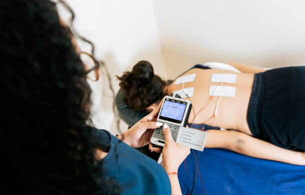 istock View of physiotherapist electrostimulating a patient. Lower back therapy with electrode pads. Electrode treatment to patient lying down, Professional physiotherapist electrostimulating patient 1456323575