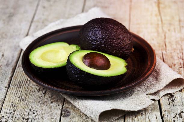 istock Fresh organic avocado on ceramic plate and linen napkin on rustic wooden table background. 1456327329