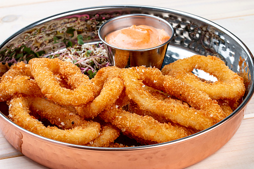 Onion rings fried in breading with cheese sauce