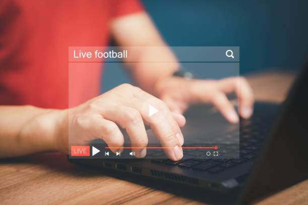istock Man using a computer laptop for watching live football streaming online on virtual screen, searching video on internet, concept of content online. 1456332788