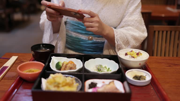 Woman in white lace kimono taking photos of Japanese foods