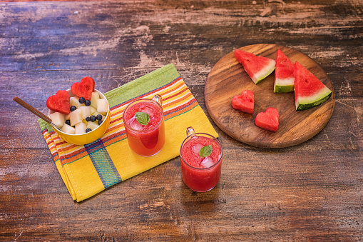 Fresh ripe watermelon piece at plate,  with glass of watermelon juice on table