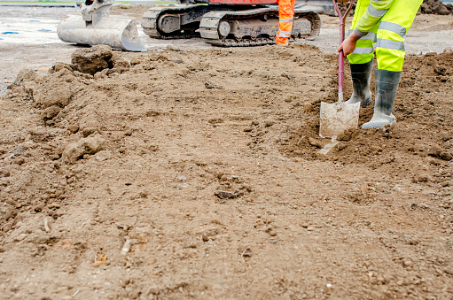 Builder using shovel to clean kerbs and footpath acidentaly covered by top soil