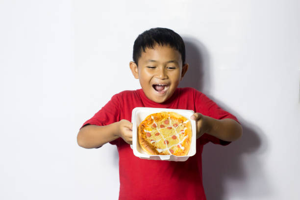 istock Asian boy eat pizza on white background 1456336181