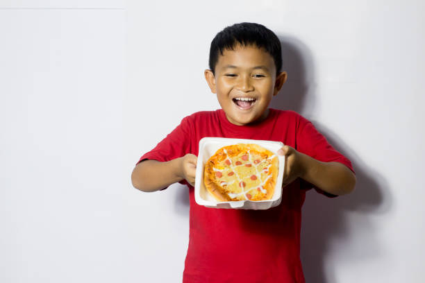 istock Asian boy eat pizza on white background 1456336835