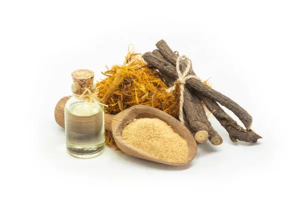 Glass bottle of licorice root essential oil with liquorice fiber and powder on rustic background ( glycyrrhiza glabra )