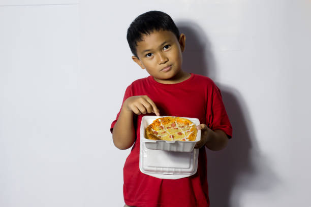 istock Asian boy eat pizza on white background 1456337159