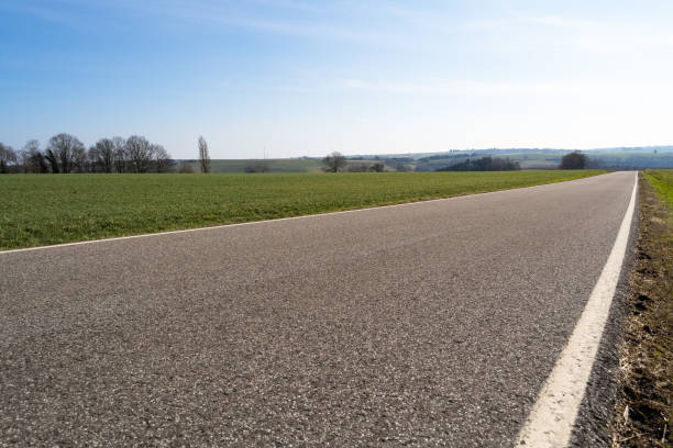 istock View of a paved rural road between grassfields in the landscape with blue sunny sky in spring 1456337191