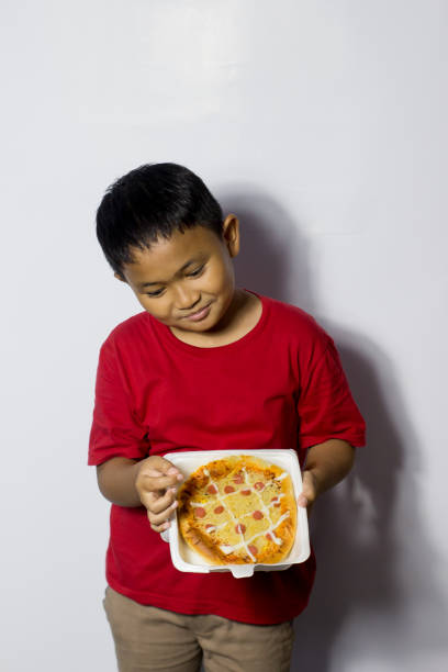 istock Asian boy eat pizza on white background 1456338380