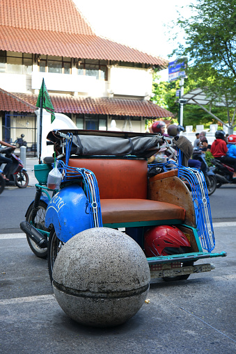 yogyakarta, indonesia
January 13, 2023
A motor-powered pedicab
 which is often called Bentor is parked on the side of the road in Maloboro, Yogyakarta.
