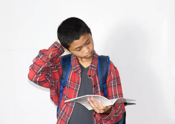 Asian boy wear casual uniform holding pen for writing a book in isolated on white background