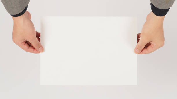 istock Two hand is holding the A4 paper board on white background. 1456347595