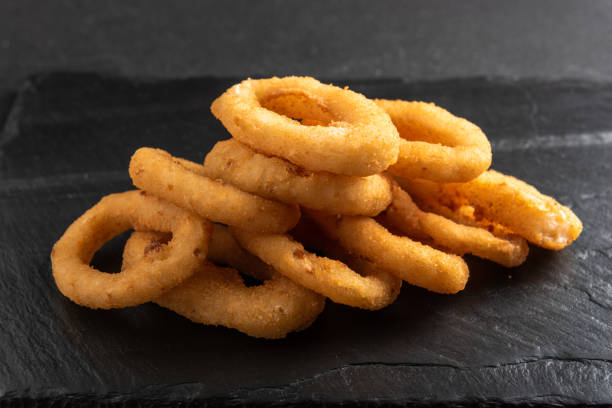istock Calamari rings deep-fried in breading. Crispy squid rings on a dark background with sauce. 1456350667
