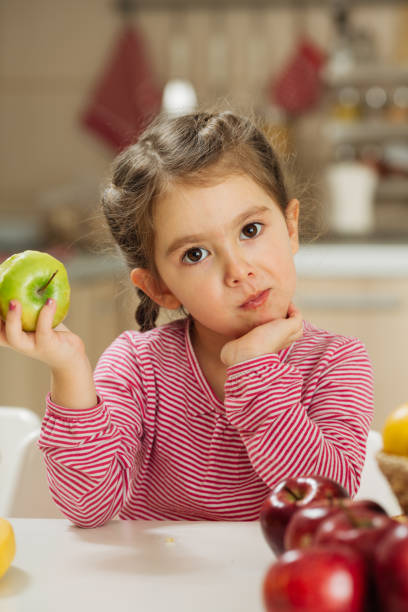 istock Smiling little girl eating apple 1456351814