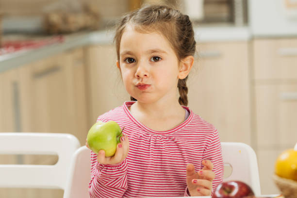 istock Smiling little girl eating apple 1456351846
