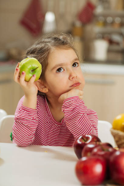 istock Smiling little girl eating apple 1456351863