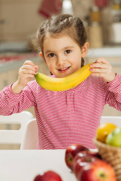istock Little girl holding banana 1456351925