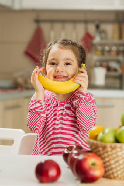 istock Little girl holding banana 1456351949