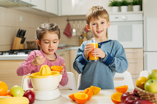 Children squeeze orange juice In the kitchen