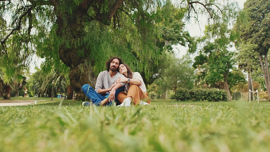 Happy smiling couple talking while sitting on blanket in park