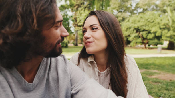 istock Happy smiling couple talking while sitting on blanket in park. Close-up 1456352407
