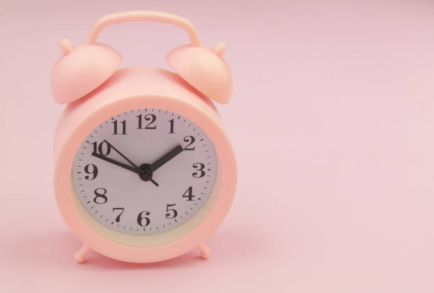 istock Pink alarm clock on pink background 1456352633
