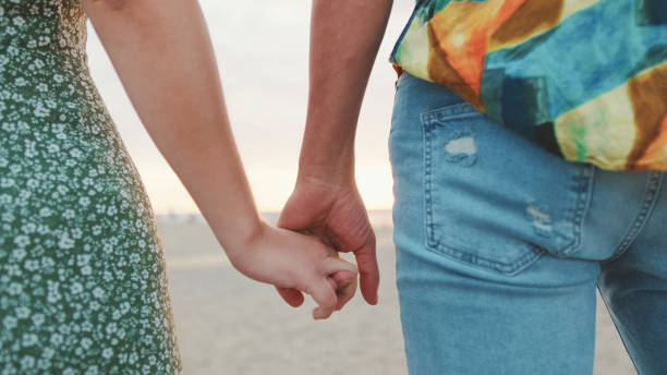 istock Closeup young couple holding hands on sea background. Back view 1456352884