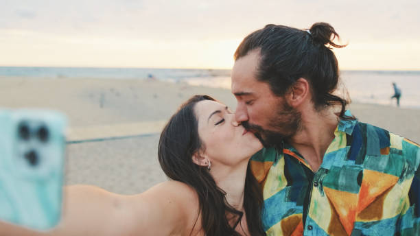 istock Young couple holding hands while standing on the beach. Back view 1456352968