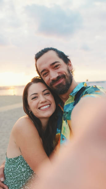istock Laughing couple making video call while standing on the beach 1456353015