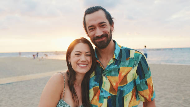 istock Young couple standing on the beach at sunrise 1456353063