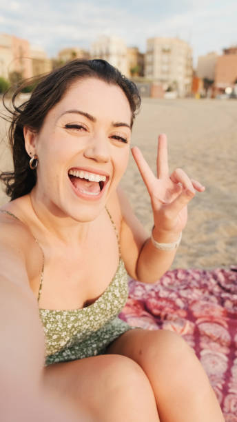 istock Young woman sitting on sandy beach and using mobile phone, making video cal 1456353165