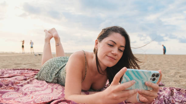 istock Young smiling woman relaxing on the beach and using mobile phone 1456353733