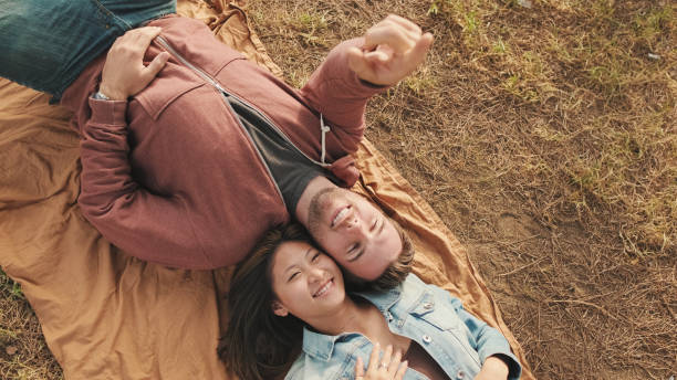 istock Young couple lying on blanket in the park. View from above 1456354023