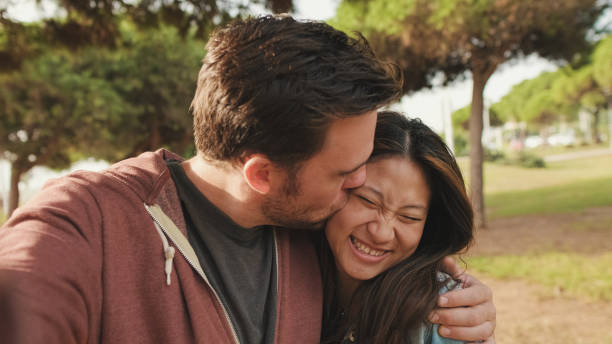 istock Close up, laughing couple hugging each other while standing in the park. looking at camera 1456354052