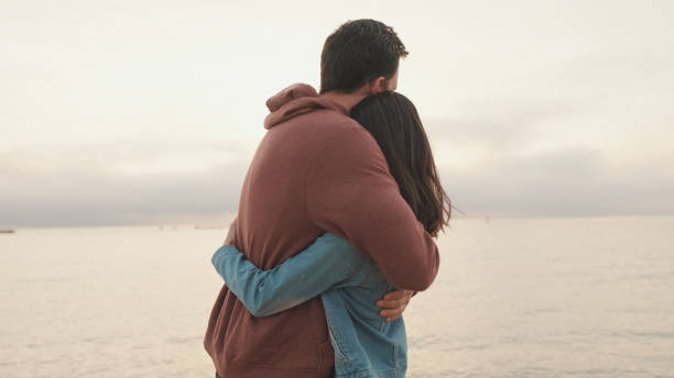 istock Young couple standing embracing on seascape background. Back view 1456354081