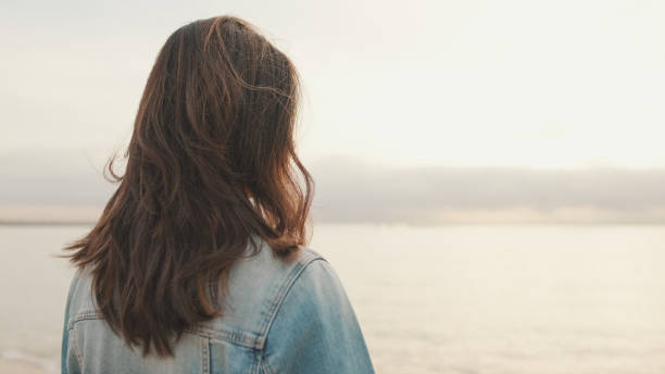 istock Young beautiful woman walking on the beach. Back view 1456354144