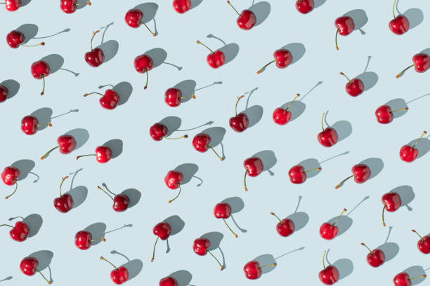 istock Red cherry fruits on sunny blue background. Creative summer fruits pattern concept. 1456354434