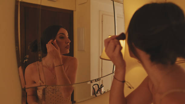 istock Close up, young woman putting on makeup while standing in front of mirror 1456355567