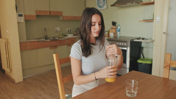istock Close up, young woman drinking orange juice while sitting in the kitchen 1456355594