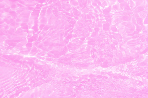 Defocus blurred transparent pink colored clear calm water surface texture with splashes and bubbles. Trendy abstract nature background. Water waves in sunlight with copy space. Pink water shining.