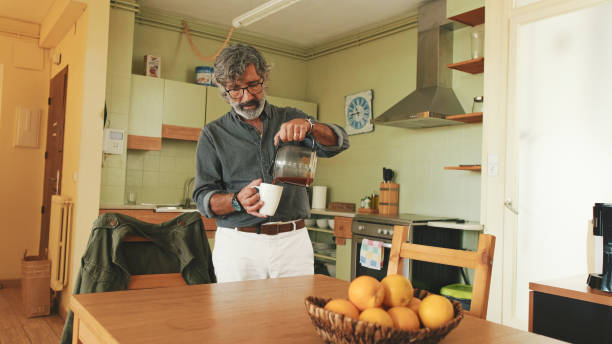 istock Elderly man pouring coffee into cup in the home in the kitchen 1456355895