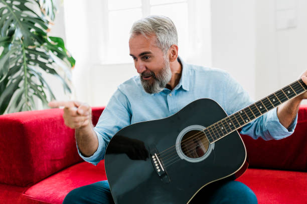 istock Senior man playing guitar at home 1456355930