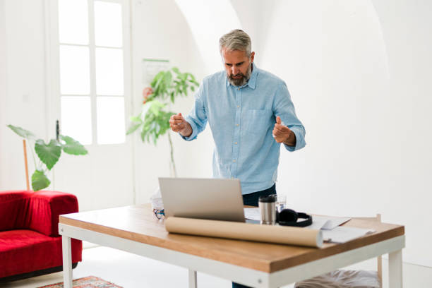 istock Shot of a senior businessman looking angry while using a laptop work 1456357100