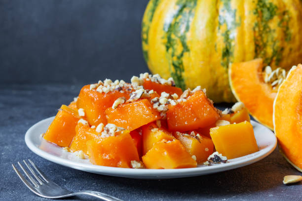 Traditional Turkish Pumpkin Dessert with sherbet on rustic table and fresh sliced pumpkins stock photo